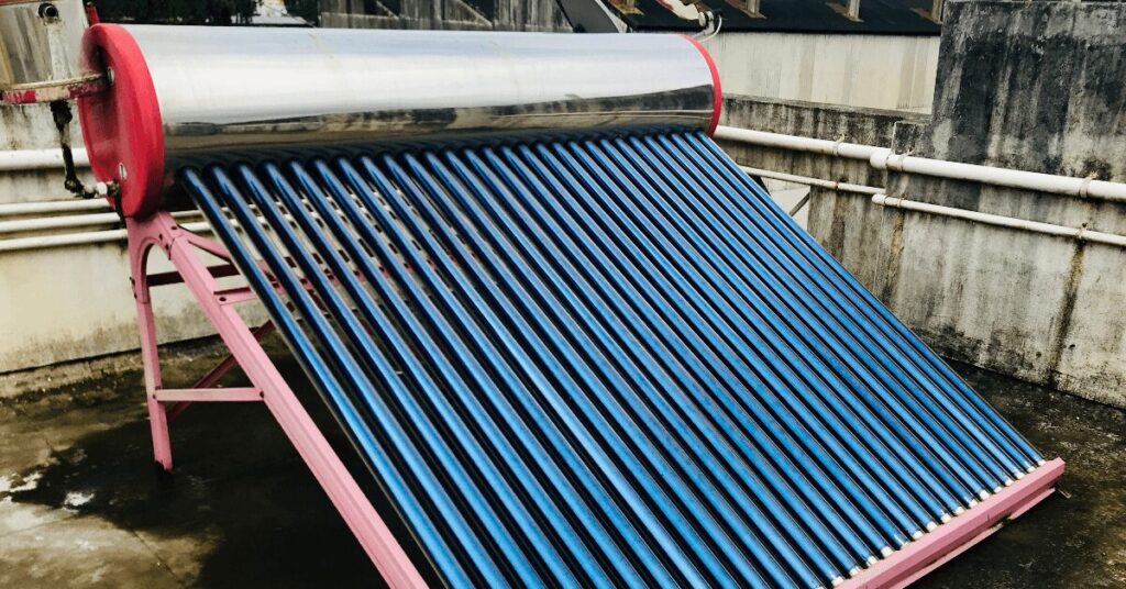 Rooftop solar thermal collector with blue vacuum tubes on a pink metal frame on a concrete surface