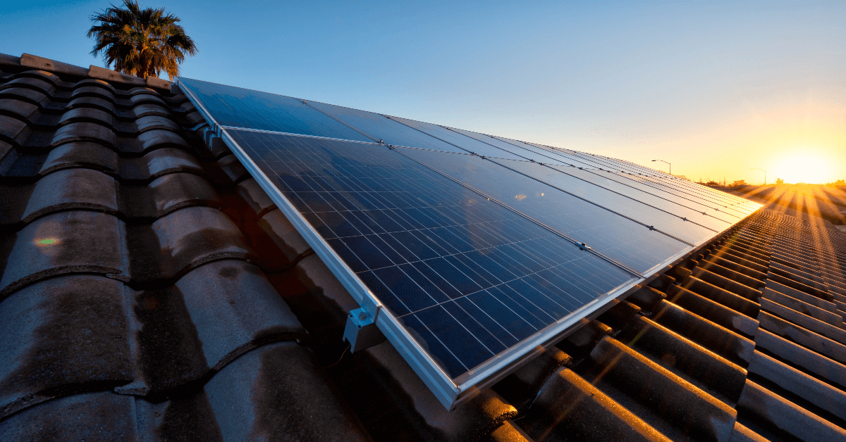 Solar panels installed on a tiled roof at sunset, capturing sunlight for renewable energy.