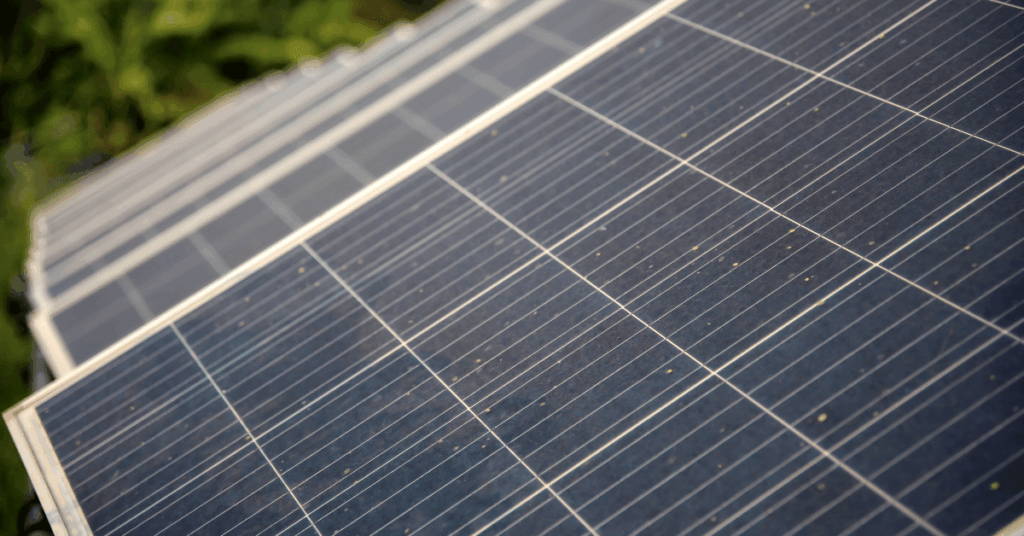 Row of solar panels on a sloped roof, capturing sunlight with visible grid lines and edges.