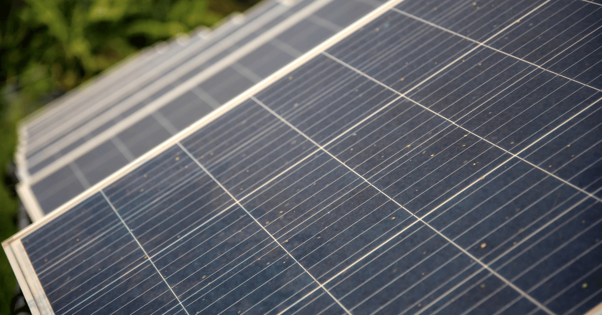 Row of solar panels on a sloped roof, capturing sunlight with visible grid lines and edges.