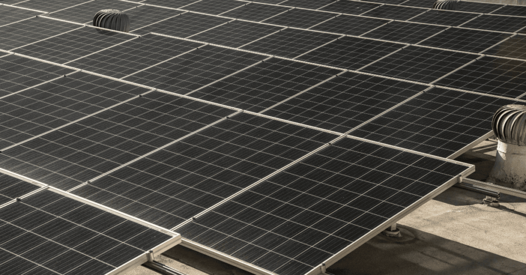Close-up view of dark blue solar panels installed on a flat rooftop, arranged in neat rows may be used for solar energy generation.