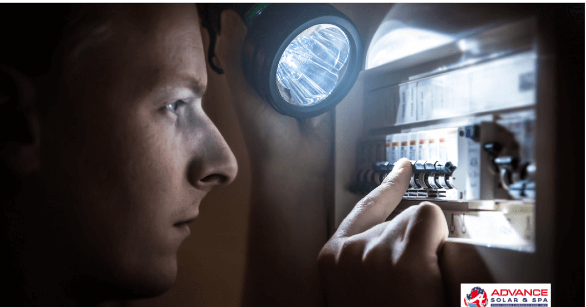 Technician inspecting a circuit breaker panel with a bright flashlight in a dim room.