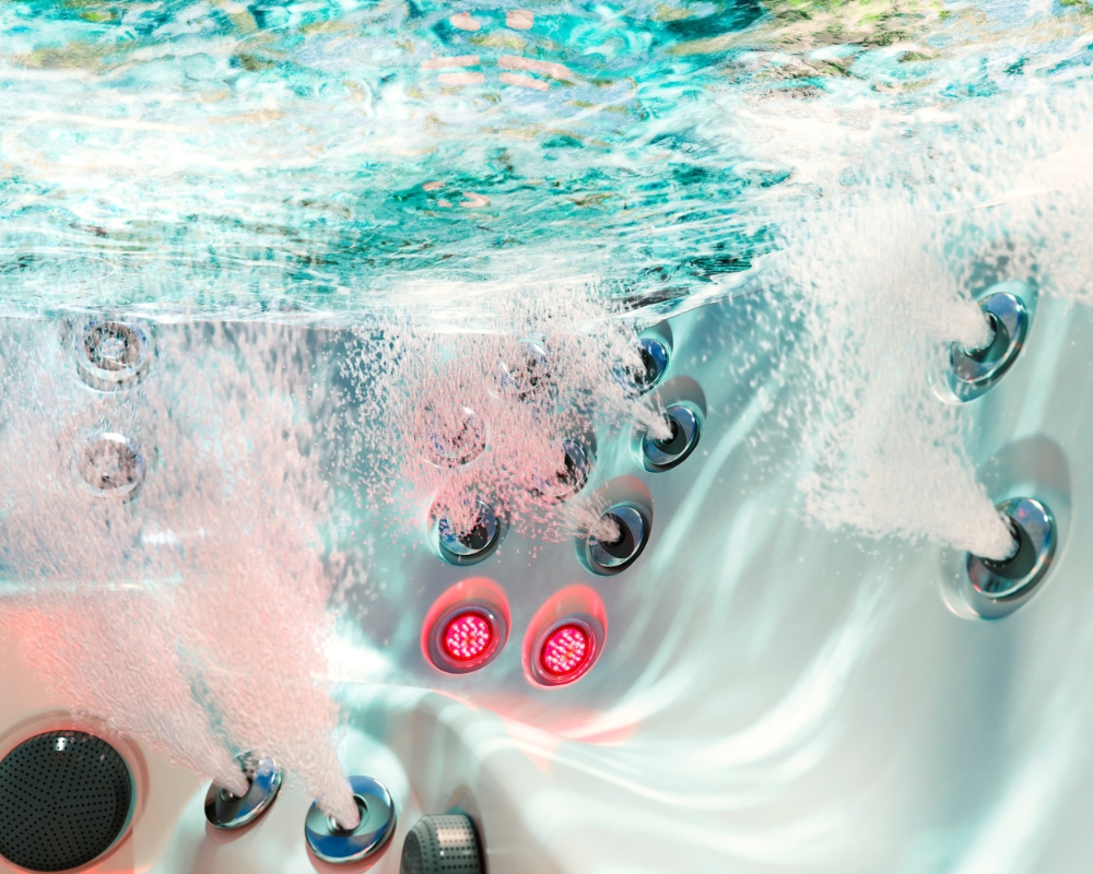 Hot tub interior with multiple jet nozzles spraying water and red LED lights.