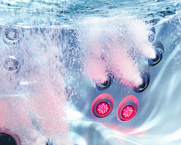 Close-up of a hot tub or spa with red LED jets and bubbling water underwater.