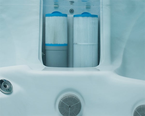 Two blue-capped water filter cartridges inside a white home filtration unit.