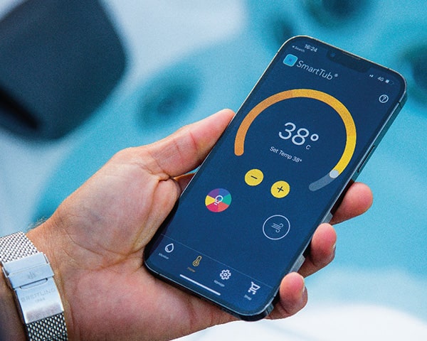 Hand holding a smartphone displaying a thermostat app with a circular temperature gauge reading 38°C.