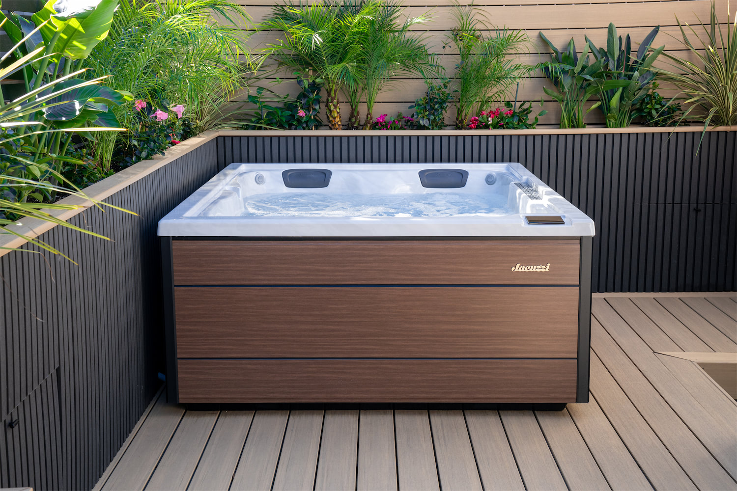 Luxurious outdoor hot tub with a wooden exterior on a deck, surrounded by tropical plants and greenery.