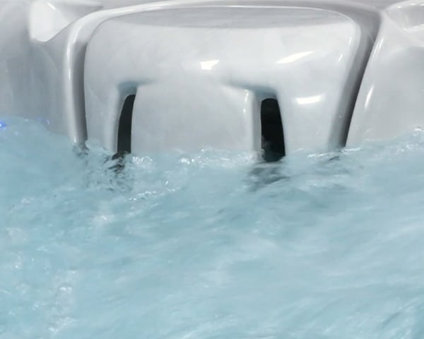 White hot tub or spa with two vertical jet openings partially submerged as water swirls around them.