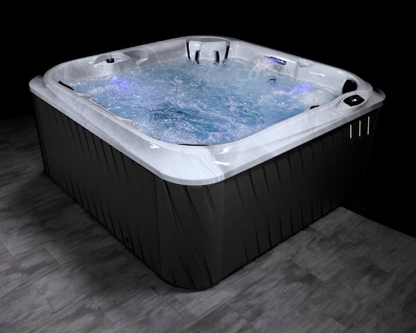 Black rectangular hot tub with bubbling water, white interior, on a dark wooden floor.