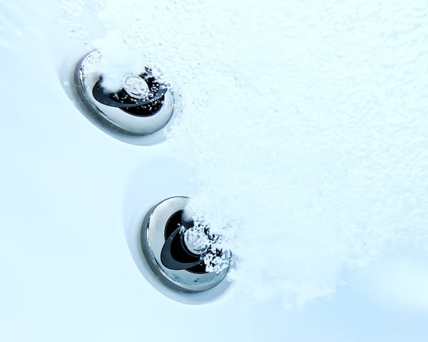 Two chrome drain covers set in a frosted, snow-like surface.
