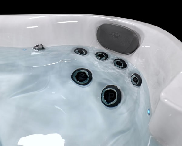 White hot tub interior with multiple circular water jets and a built-in gray speaker on the inner wall.