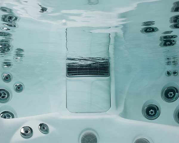 Underwater view inside a white hot tub with multiple round jets along the walls and a central rectangular seat/step area.