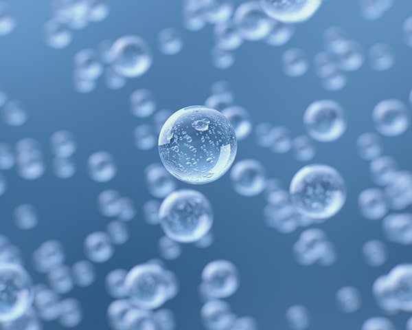 Close-up of translucent bubbles floating in a blue liquid, with one bubble in sharp focus at the center.